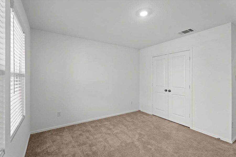 A well-lit bedroom features plush carpeting and a spacious closet. A well-lit bedroom features plush carpeting and a spacious closet.