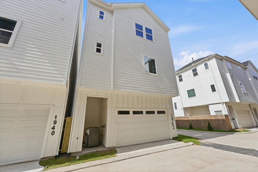 Modern rear exterior featuring a two-car garage, private driveway, and clean contemporary siding within a well-maintained townhome community.