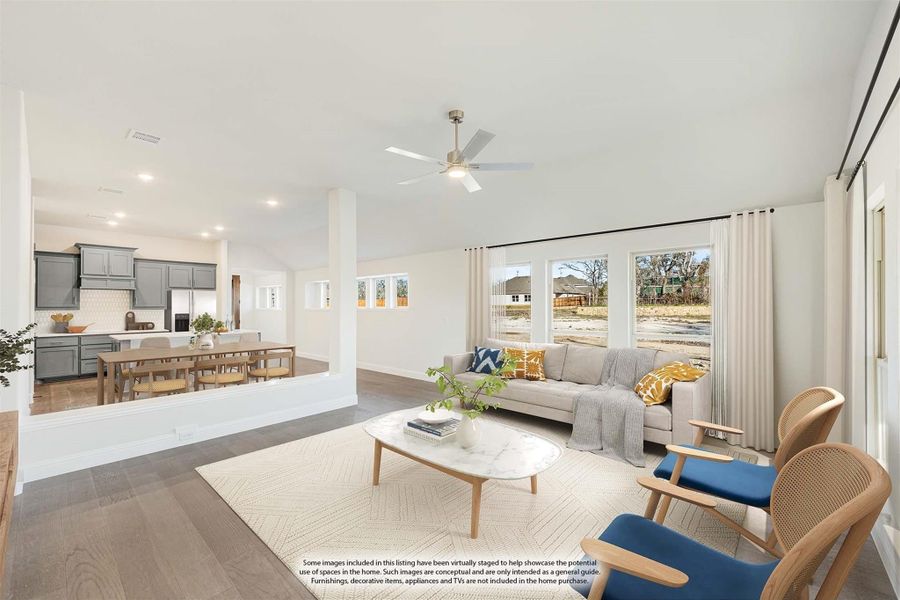 Open-concept living room with ceiling fan, hardwood floors, and kitchen visible in background