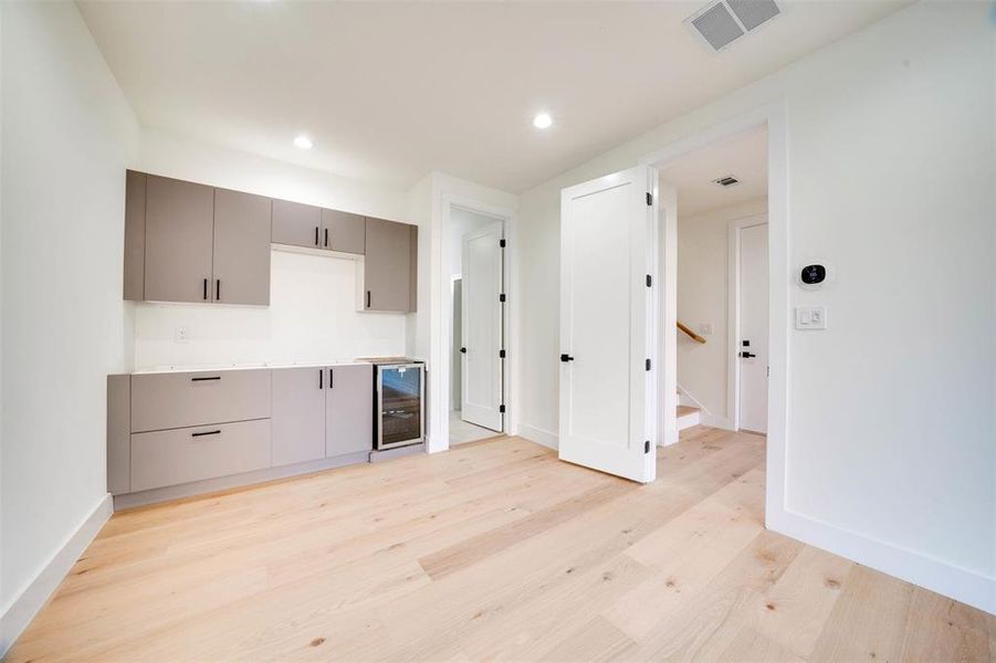 Kitchen with gray cabinets, beverage cooler, and light wood-type flooring