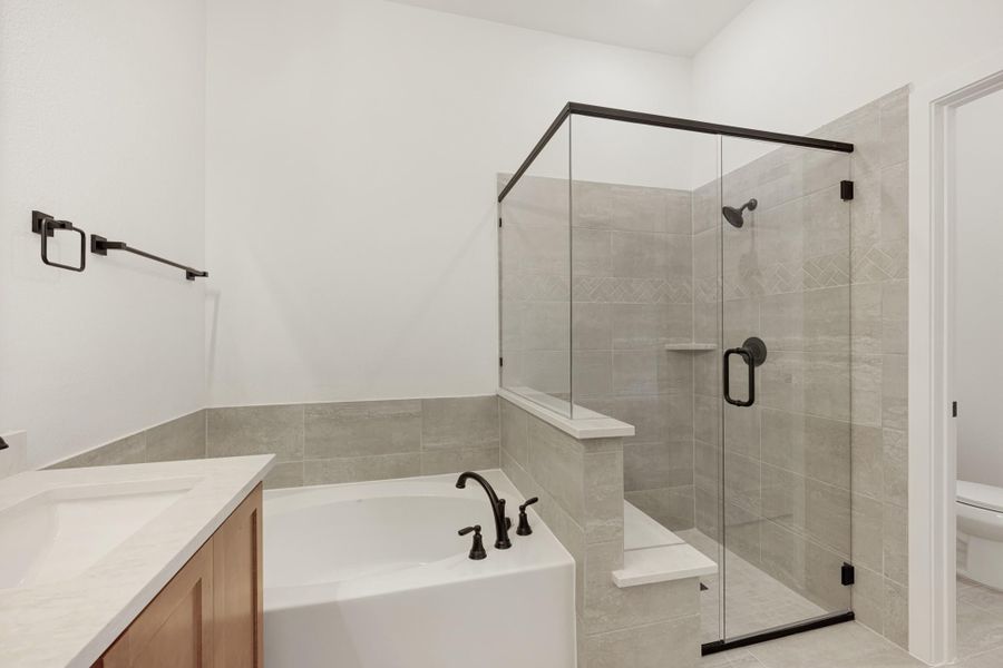 Master bathroom with soaking tub, glass walk-in shower, gray tile walls, and dark bronze fixtures