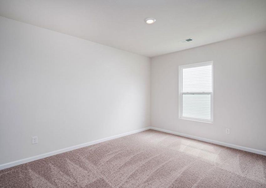 Secondary bedroom with a window, blinds, tan carpet and walls.