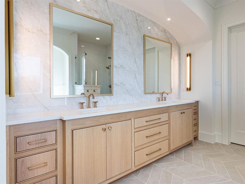 Primary bathroom with white oak cabinetry, double sinks, designer lighting and look at that backsplash!