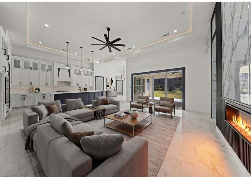 Virtually Staged - Living room featuring a high end fireplace, a ceiling fan, light marble finish floors, and a raised ceiling
