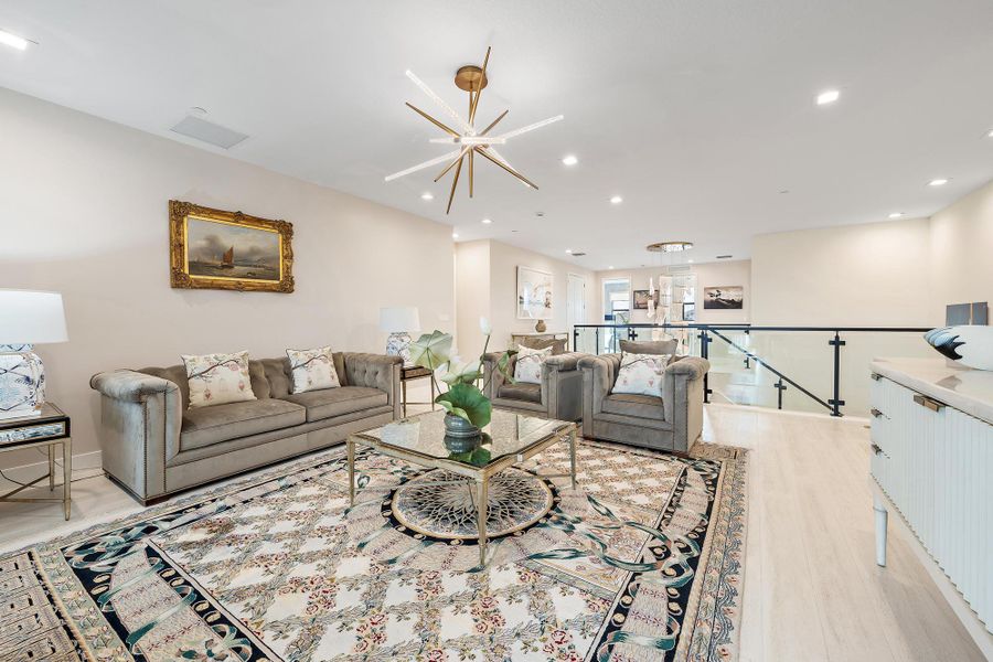 Spacious 2nd-floor loft with upgraded wood flooring, custom lighting, and high-end glass railing to the stairs.