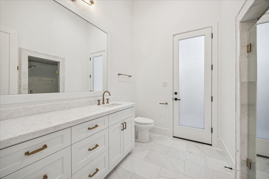 Located off the main staircase with direct outdoor access, the pool bath features marble finishes, brass fixtures, and a freestanding shower. Guests can enter from outside, preserving the home’s main living spaces during pool days or entertaining. *Previous Project*