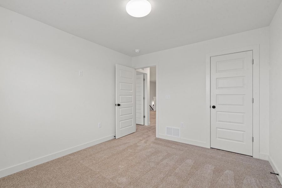 Neutral wall paint with textured carpeting, paneled interior doors, and a flush-mount ceiling light