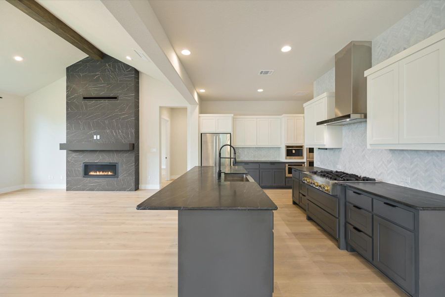 A spacious, open-concept living area features a grand fireplace and a chef-ready kitchen.