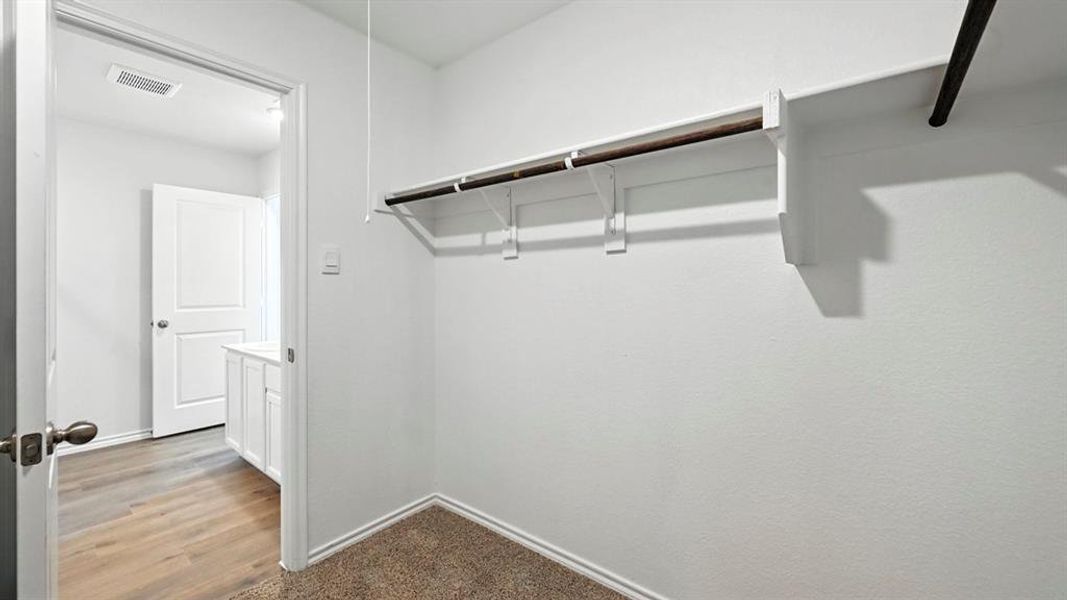 Walk-in closet featuring built-in shelving and hanging rods Walk-in closet featuring built-in shelving and hanging rods