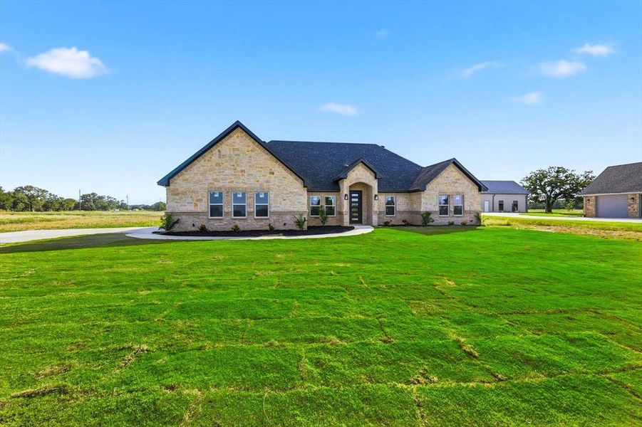 French provincial home featuring a front lawn and stone siding