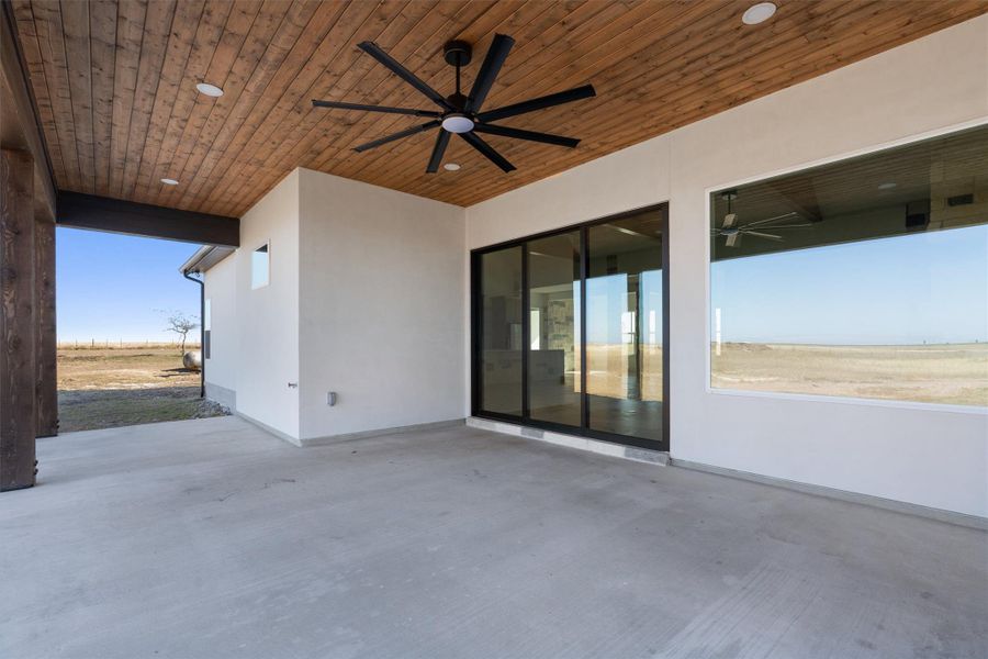 An inviting covered patio featuring a wood plank ceiling and a large ceiling fan provides an ideal outdoor living space. An inviting covered patio featuring a wood plank ceiling and a large ceiling fan provides an ideal outdoor living space.