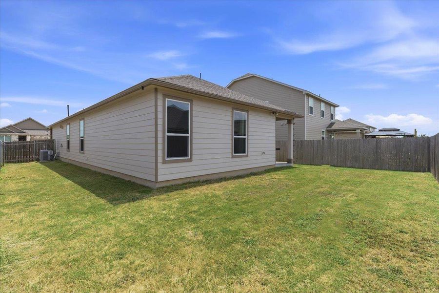 A well-maintained side yard offers ample green space and a durable privacy fence.