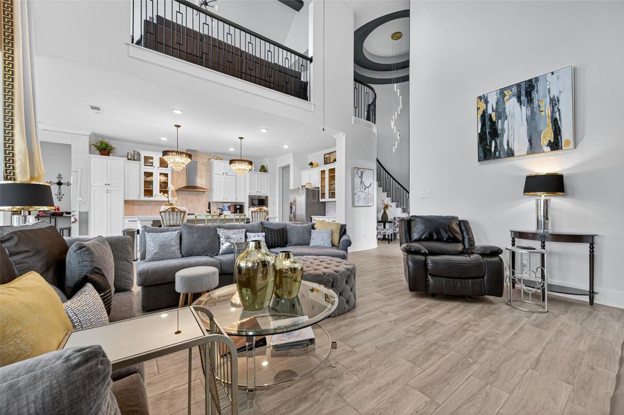 This spacious, modern living area features high ceilings and an open-concept design, seamlessly connecting to a stylish kitchen. The room is elegantly furnished with comfortable seating, contemporary decor, and abundant natural light. A striking staircase adds architectural interest, making it ideal for both relaxation and entertaining. This spacious, modern living area features high ceilings and an open-concept design, seamlessly connecting to a stylish kitchen. The room is elegantly furnished with comfortable seating, contemporary decor, and abundant natural light. A striking staircase adds architectural interest, making it ideal for both relaxation and entertaining.