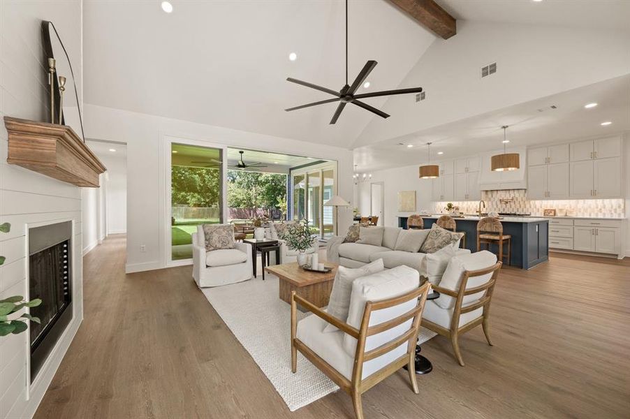 Living room with recessed lighting, a fireplace, light wood-type flooring, beamed ceiling, and high vaulted ceiling Living room with recessed lighting, a fireplace, light wood-type flooring, beamed ceiling, and high vaulted ceiling