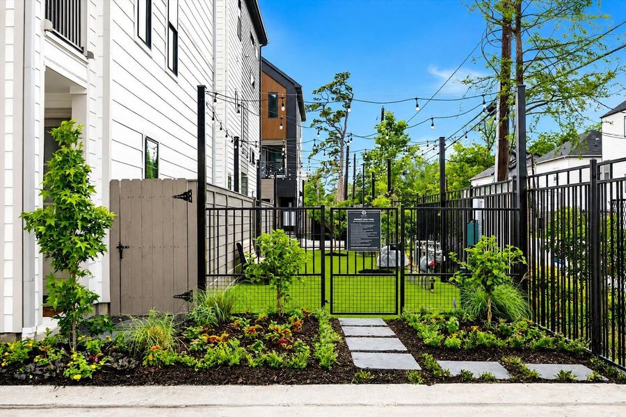 Landscaped outdoor space with turf, paver walkways, and gated privacy
