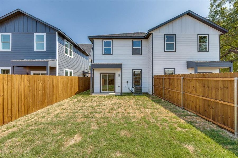 Rear view of house with board and batten siding and a fenced backyard Rear view of house with board and batten siding and a fenced backyard