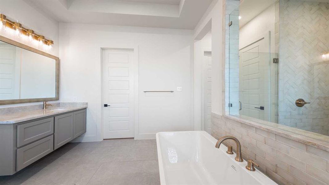 Bathroom featuring vanity, a raised ceiling, separate shower and tub, and tile patterned floors