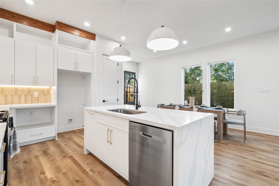 The kitchen is illuminated by dome pendant lighting over the island and undermounted LED ceiling lights, enhancing the bright and airy feel. The kitchen is illuminated by dome pendant lighting over the island and undermounted LED ceiling lights, enhancing the bright and airy feel.