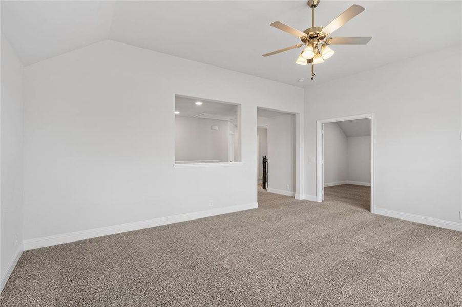 Carpeted empty room featuring lofted ceiling and a ceiling fan