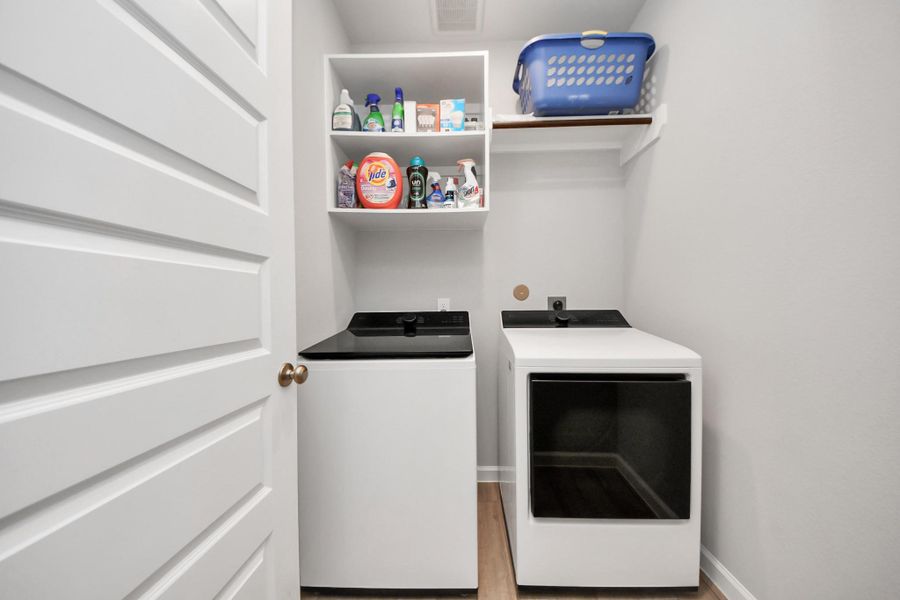 This photo shows the laundry room featuring a washer and dryer, shelving for storage, and a clean, bright aesthetic. This photo shows the laundry room featuring a washer and dryer, shelving for storage, and a clean, bright aesthetic.