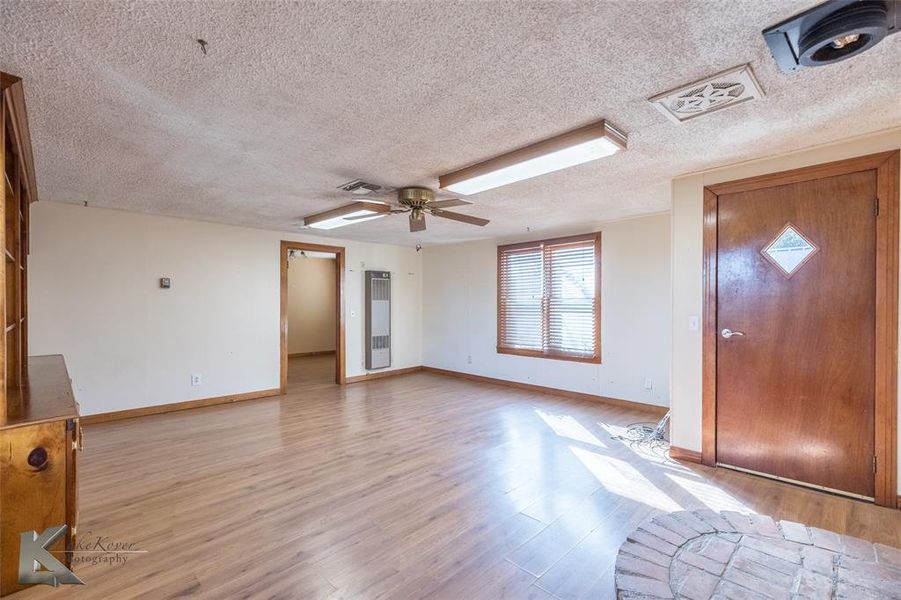 Entrance foyer with light wood-type flooring, a textured ceiling, ceiling fan, and a heating unit Entrance foyer with light wood-type flooring, a textured ceiling, ceiling fan, and a heating unit