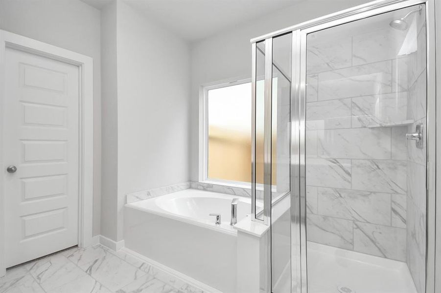 This additional view of the primary bath features a walk-in shower with the tile surround and separate garden tub perfect for soaking after a long day. Sample photo of completed home with same plan. Actual colors and selections may vary.