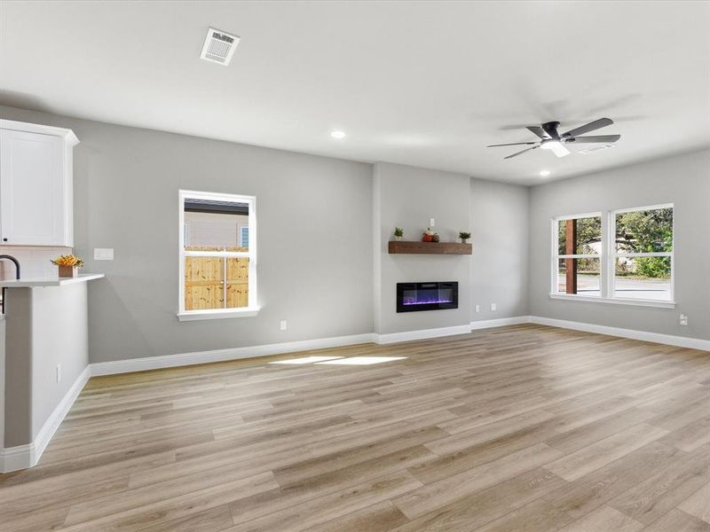 Unfurnished living room featuring light wood-style floors, a glass covered fireplace, recessed lighting, and ceiling fan Unfurnished living room featuring light wood-style floors, a glass covered fireplace, recessed lighting, and ceiling fan