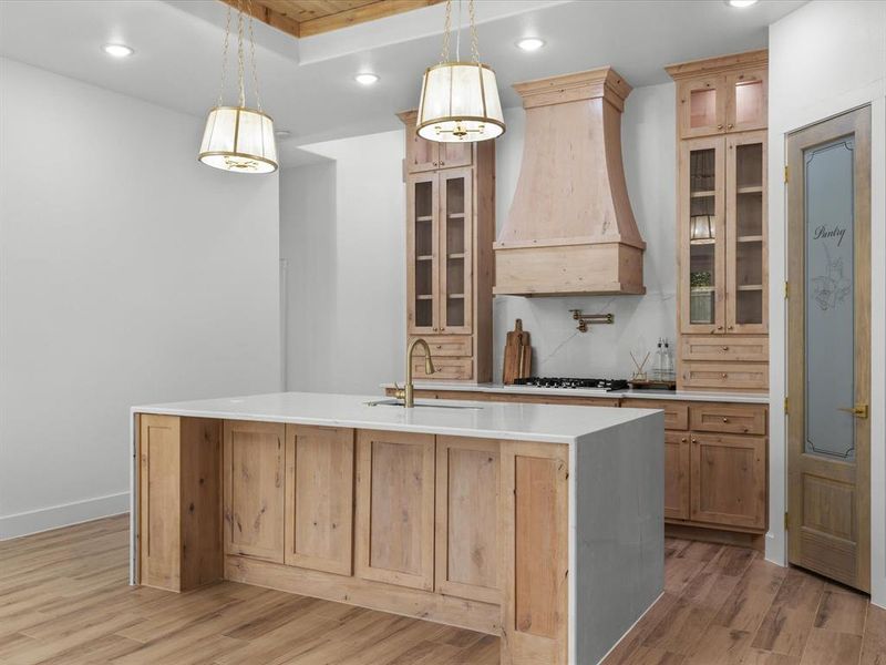 Kitchen featuring recessed lighting, light stone countertops, glass insert cabinets, pendant lighting, and light brown cabinetry