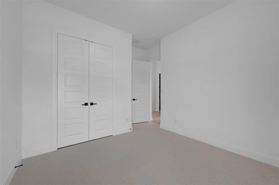 Unfurnished bedroom with light colored carpet and a closet