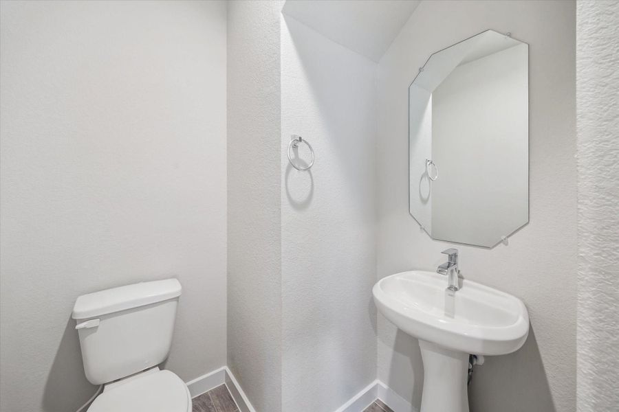 This is a compact, modern half-bathroom featuring a pedestal sink, a toilet, and a stylish mirror. The space is bright and clean with neutral wall colors and a minimalist design. This is a compact, modern half-bathroom featuring a pedestal sink, a toilet, and a stylish mirror. The space is bright and clean with neutral wall colors and a minimalist design.