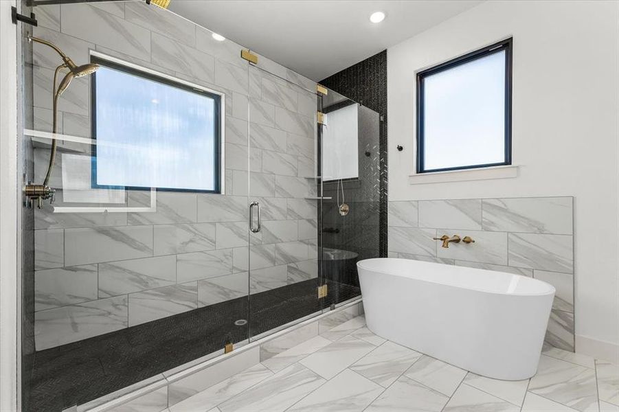 The star of the show - this expansive shower features dual shower heads, large, frosted gallery window for natural warm light, floor to ceiling contrasting tile, and large glass paneling to increase its luxurious feel.