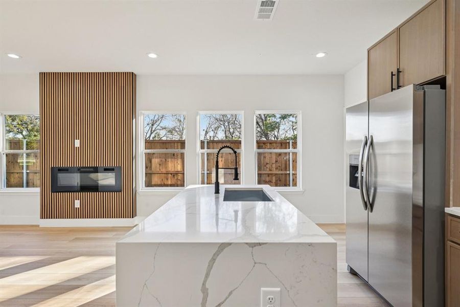 Kitchen with stainless steel fridge, light stone countertops, recessed lighting, plenty of natural light, and light wood-type flooring