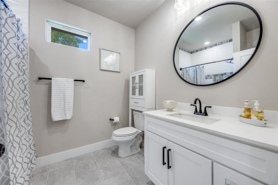 Bathroom with vanity, curtained shower, and light tile patterned flooring
