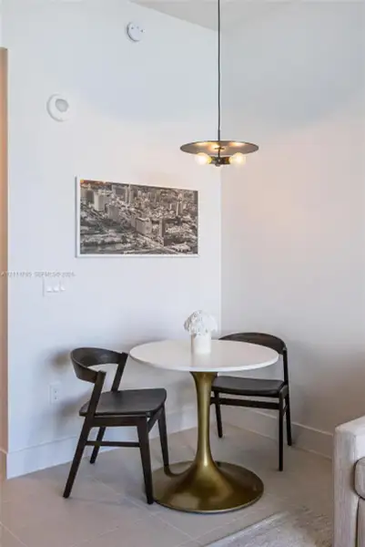 Minimalist dining area featuring stone-look tile flooring and a multi-bulb disc-style pendant light