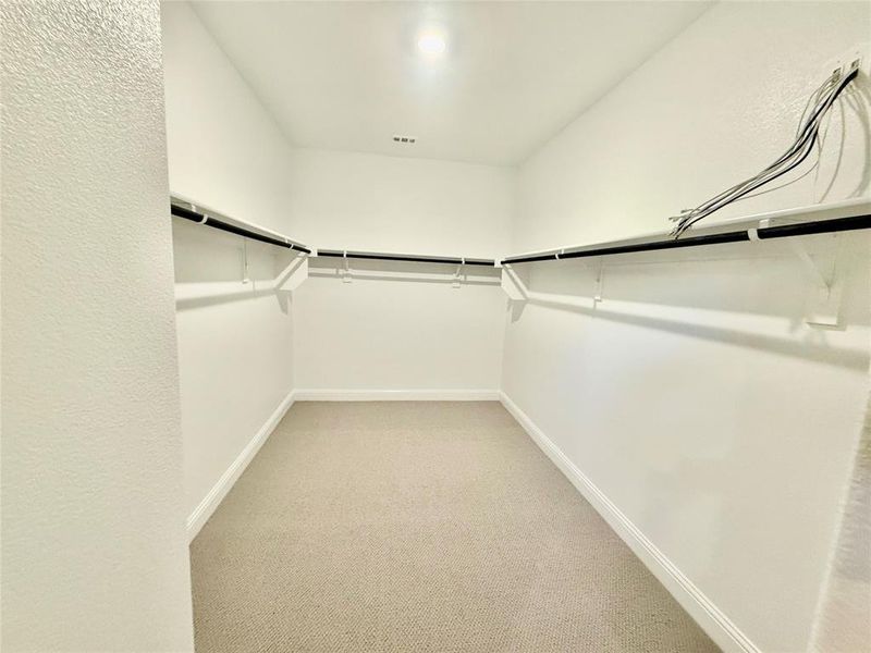 Walk-in closet featuring light-colored carpet, white walls, white trim, and built-in white shelving with hanging rods Walk-in closet featuring light-colored carpet, white walls, white trim, and built-in white shelving with hanging rods