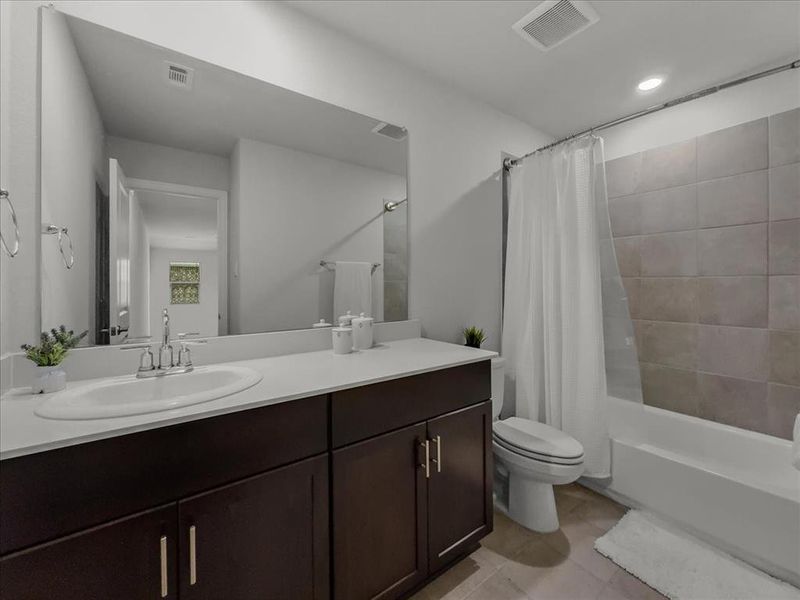 Full bathroom with toilet, tile patterned floors, shower / bathtub combination with curtain, and vanity