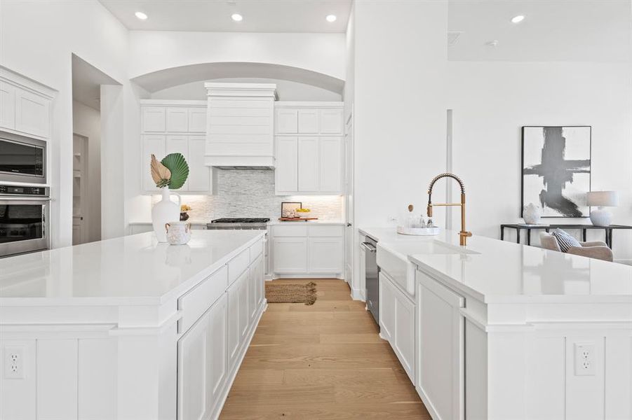 Kitchen with recessed lighting, white cabinets, appliances with stainless steel finishes, light wood-style flooring, and tasteful backsplash
