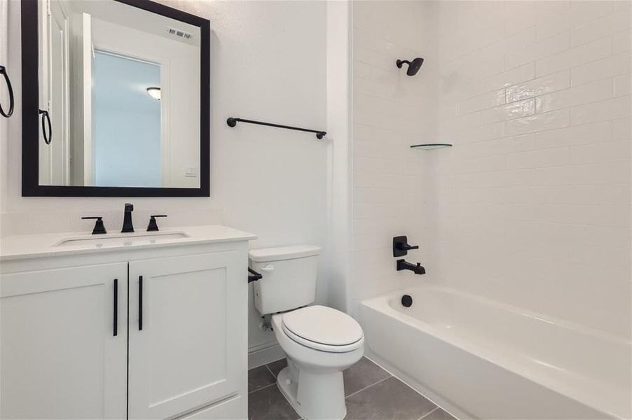 Full bathroom featuring tile floors, tiled shower / bath, toilet, and large vanity