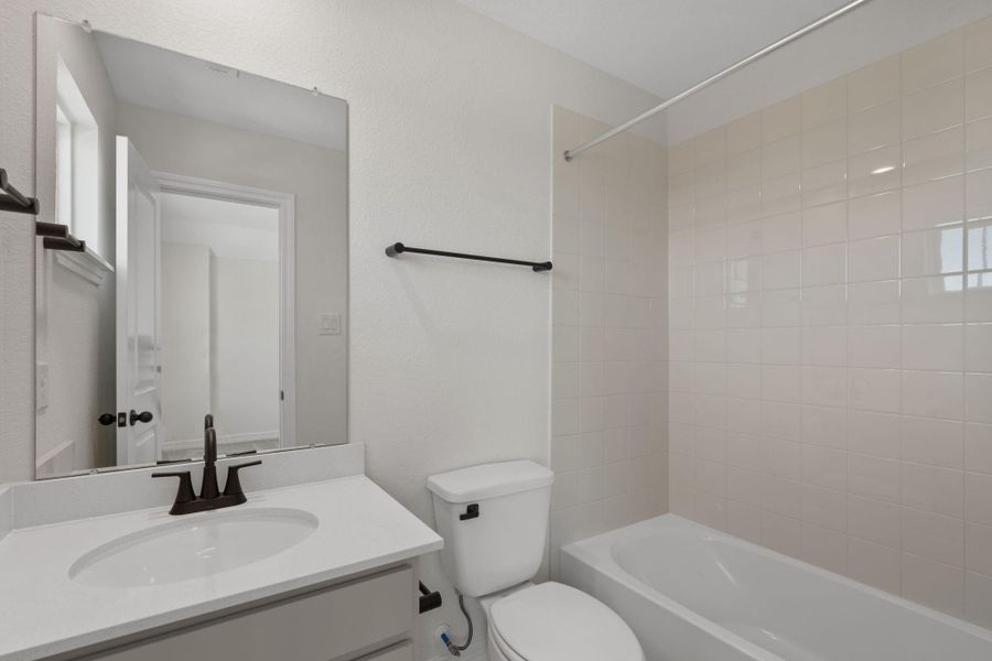The secondary bath features tile flooring, custom stained cabinetry and light countertops and a shower/tub combo. Perfect for accommodating any visiting family and friends.
