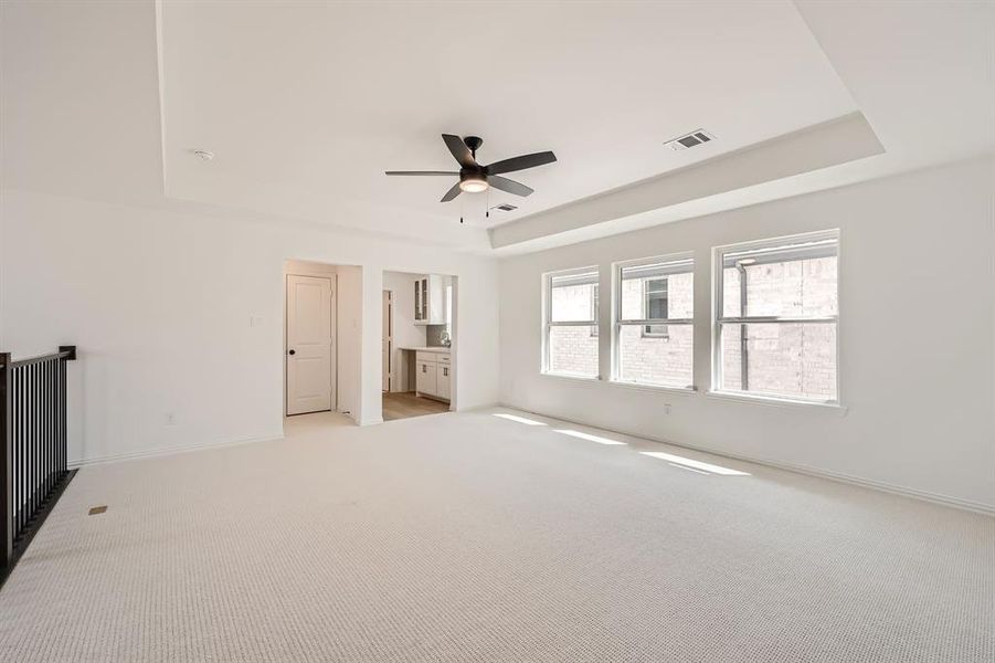 Carpeted spare room with a tray ceiling and ceiling fan