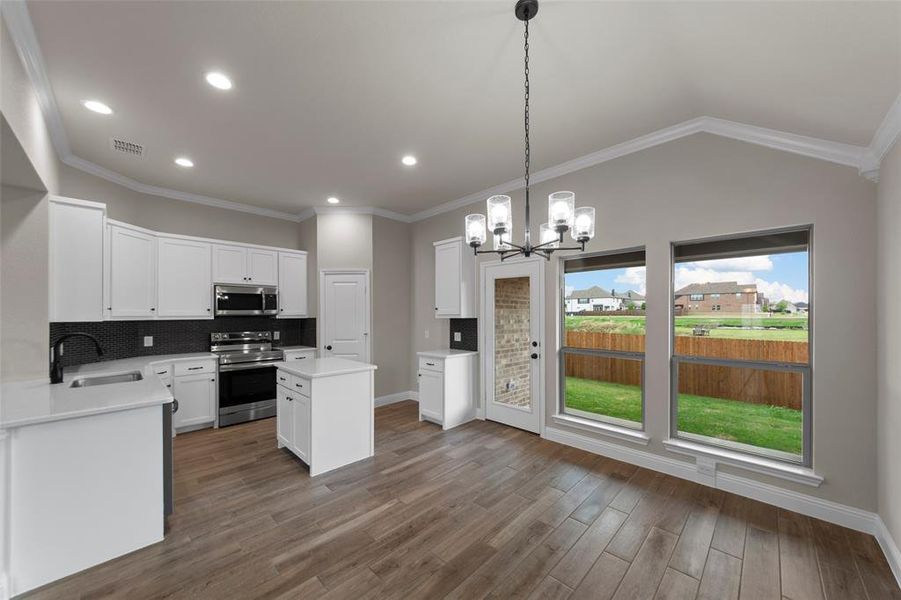 Kitchen featuring white cabinetry, stainless steel appliances, and a dark tile backsplash