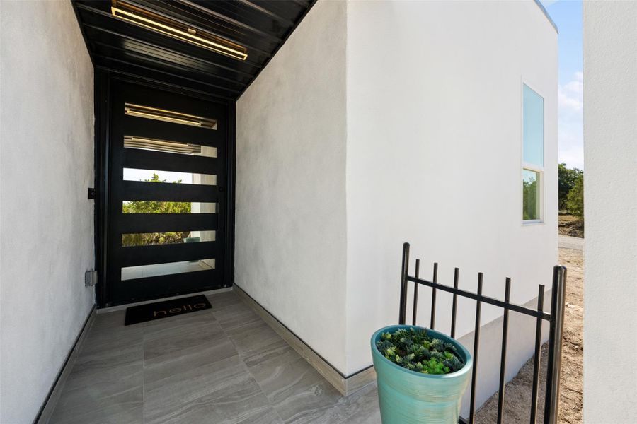 Dramatic entry with oversized tiled patio & glass & iron front door.