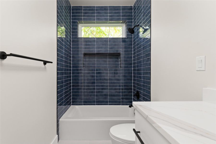 Gleaming blue subway tile surrounds the tub in this sleek, modern bathroom space.