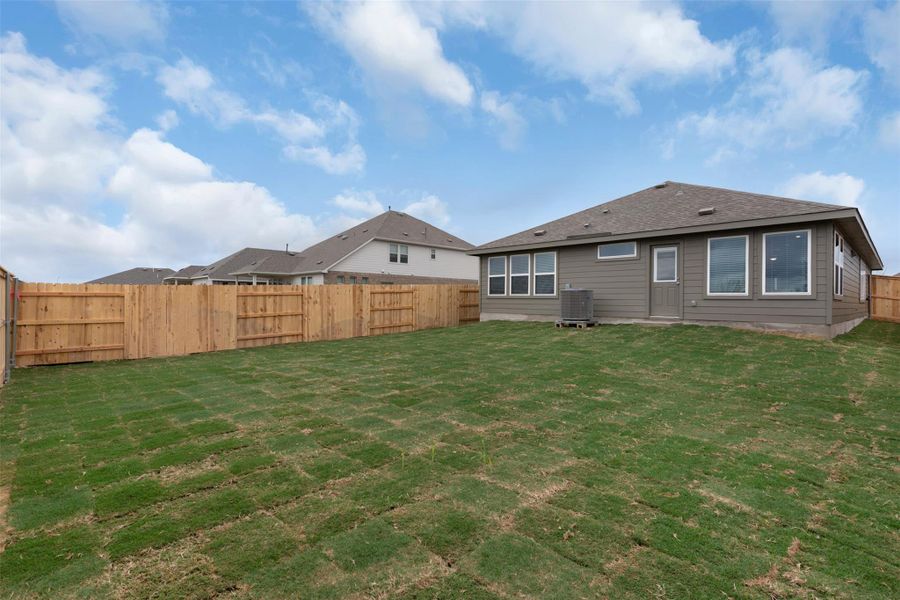 Rear view of property featuring a fenced backyard and a shingled roof