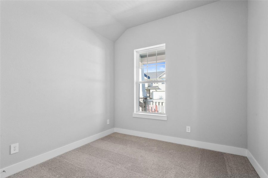 Tucked peacefully in the front of the home is this secondary bedroom. It features plush carpet flooring, neutral toned walls, and a large window.