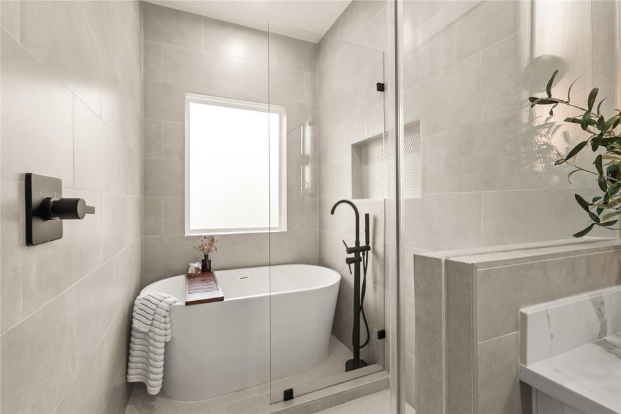 Freestanding soaking tub, matte black floor-mount filler, and a built-in tiled niche Freestanding soaking tub, matte black floor-mount filler, and a built-in tiled niche