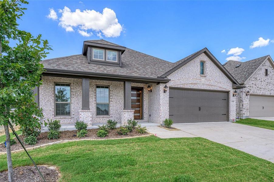 View of front of house featuring roof with shingles, covered porch, a front lawn, driveway, and brick siding View of front of house featuring roof with shingles, covered porch, a front lawn, driveway, and brick siding