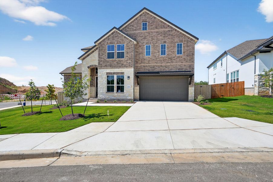 View of front of home with brick siding, stone siding, driveway, and a garage