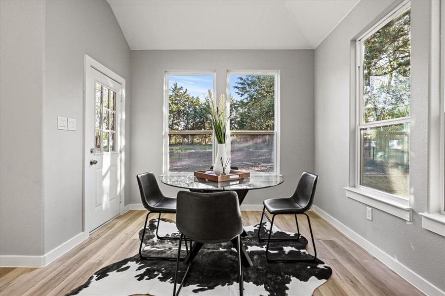 Dining area with light hardwood / wood-style floors and lofted ceiling