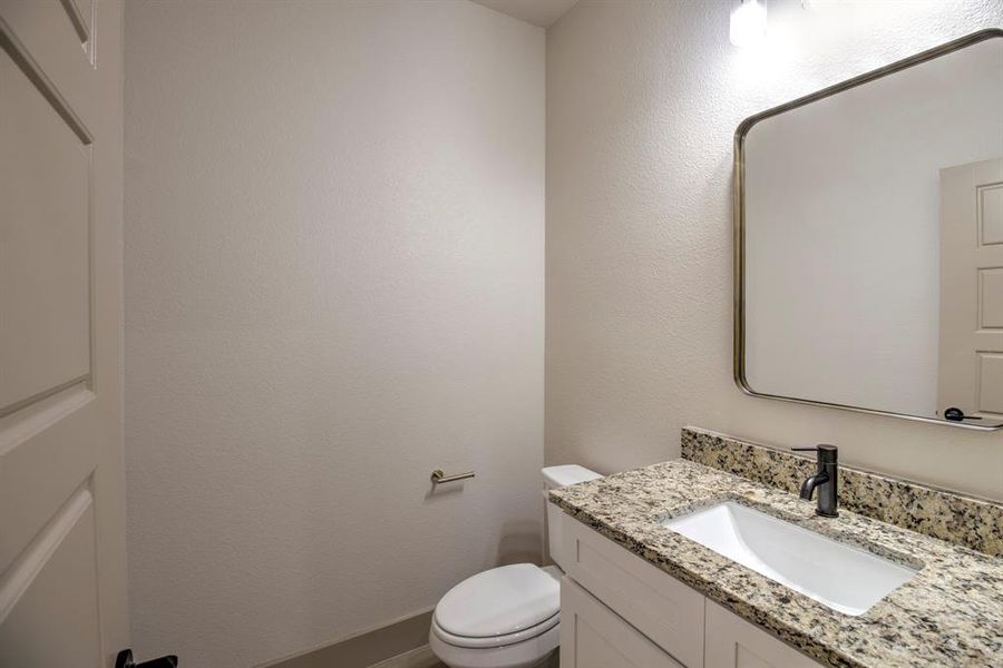 Half bath featuring a textured wall and vanity